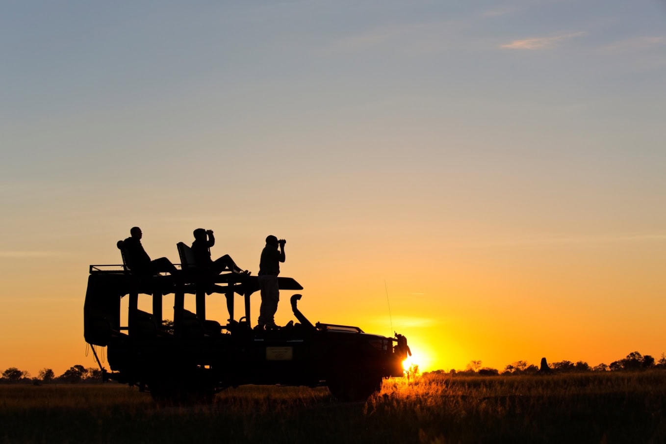 Safari Jeep met gasten zittend op het dak onderwijl genietend van de zonsondergang