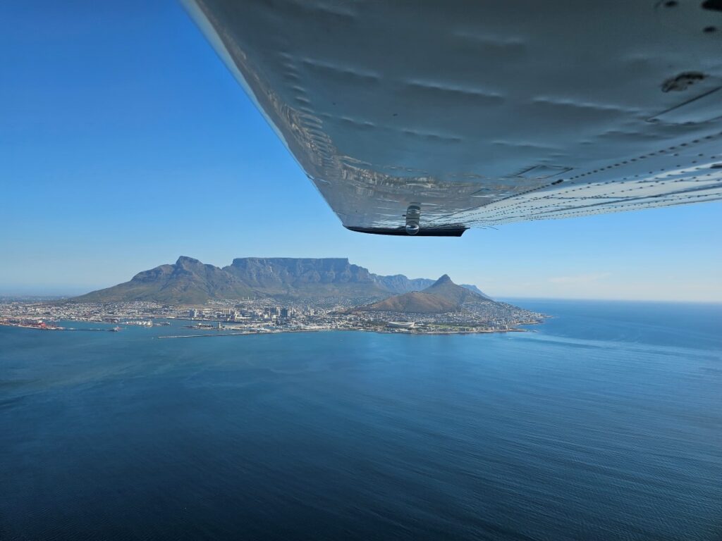 Foto van Kaapstad met de iconische Tafelberg op de achtergrond, genomen vanuit klein en laagvliegend toestel van Africa Sky Runners